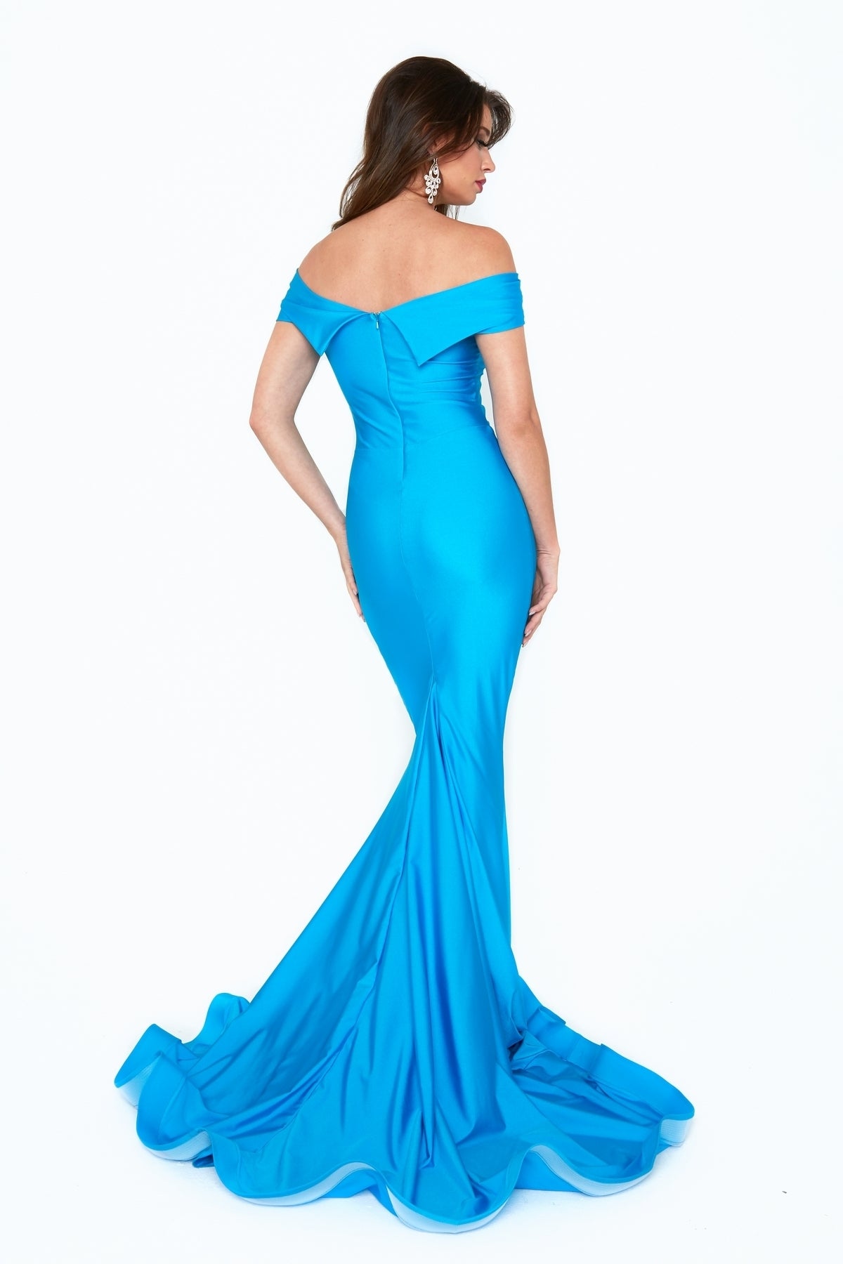 A woman stands against a white background, facing away, wearing the Atria 6204H Off-Shoulder Long Mermaid Prom Dress—a fitted, floor-length blue gown with a dramatic train.
